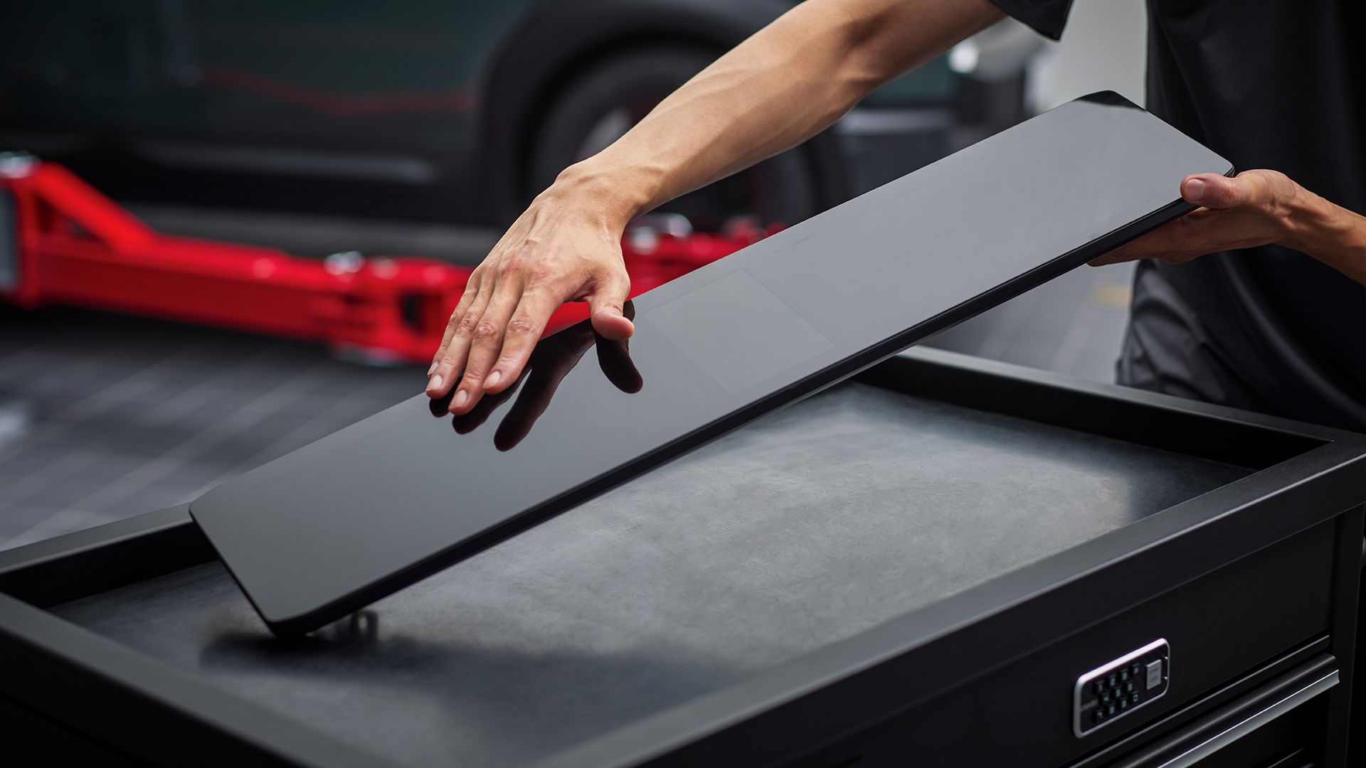 Technician handling a Kia Genuine Part on a service tool chest